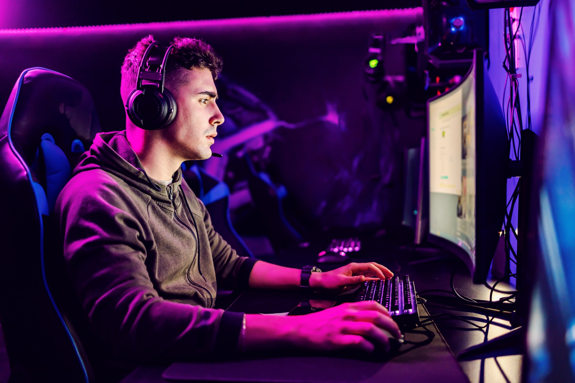 Junger Gamer mit Headset spielt konzentriert am PC im Neonlicht | Palworld Server